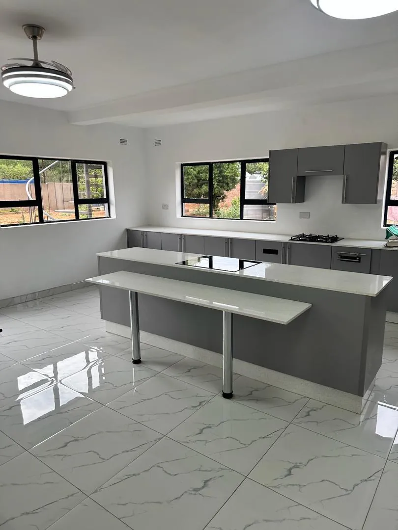 Modern kitchen with grey cabinets, a white island with a breakfast bar and marble-look floor tiles