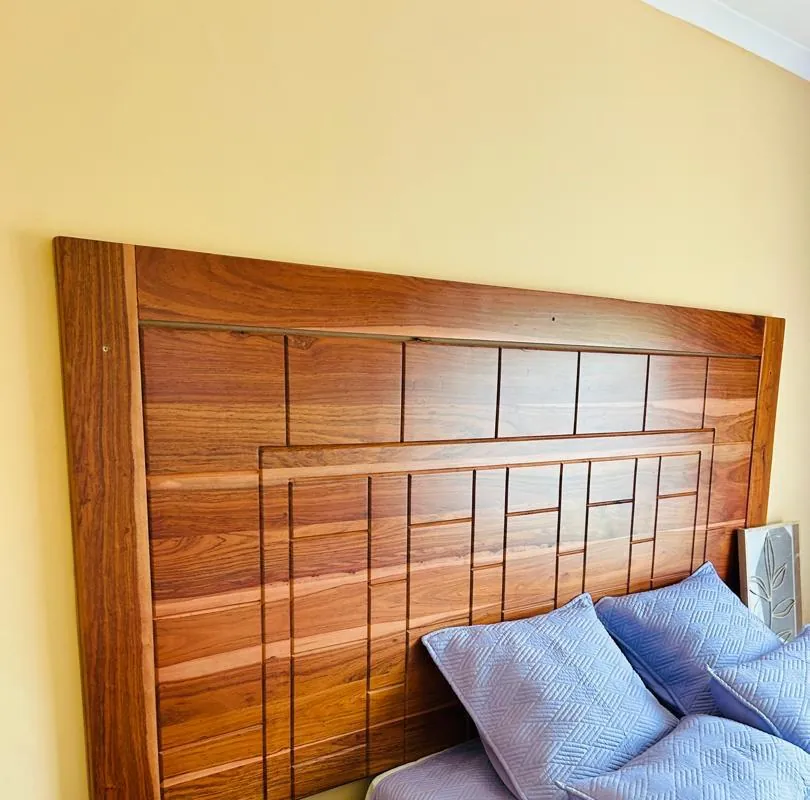 Wooden bedhead with a geometric panel pattern and lilac bedding